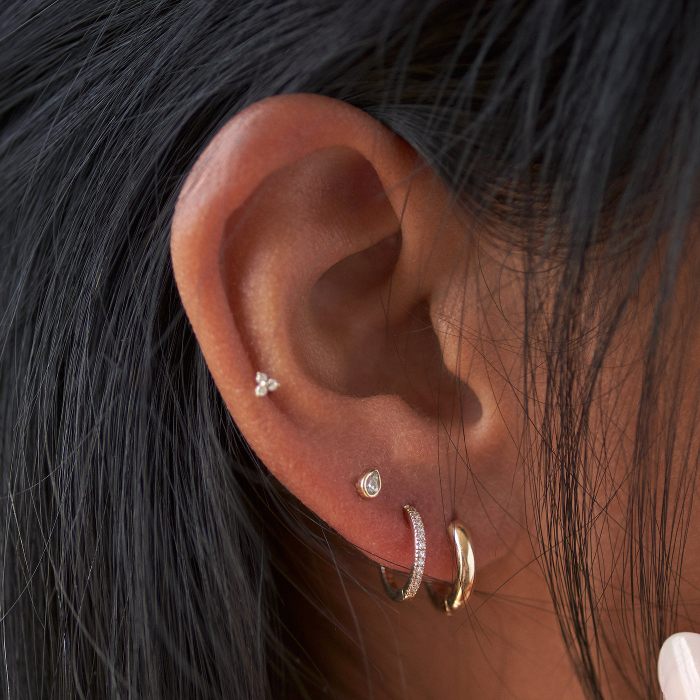 Ear show with 4 piercings. Two gold hoops and two stud earrings