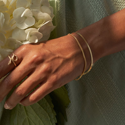 model holding flowers wearing two gold bracelets