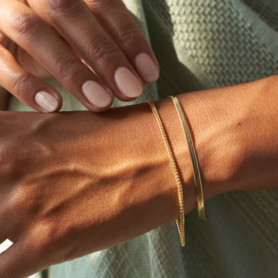 model wearing two gold bracelets