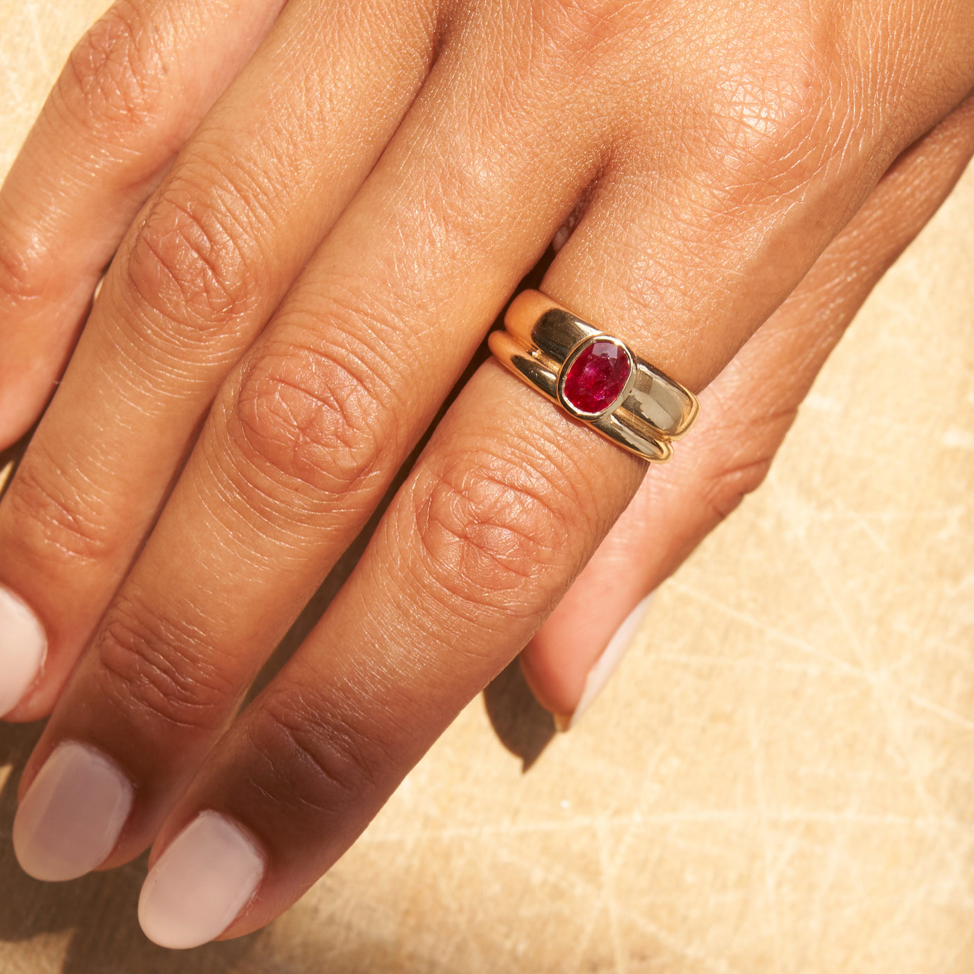 Model wearing yellow gold band ring with ruby center stone