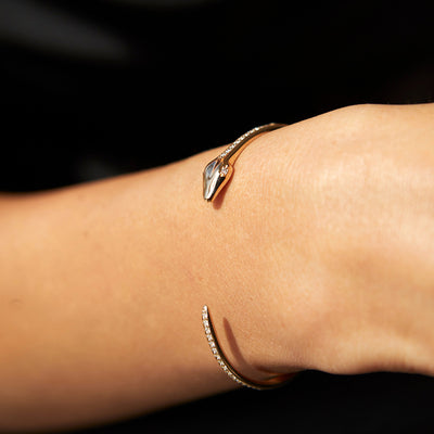 Hand model wearing a yellow gold snake cuff with diamond accents.