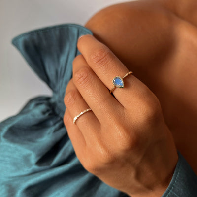 Model wearing a yellow gold ring with a pear cut labradorite stone.