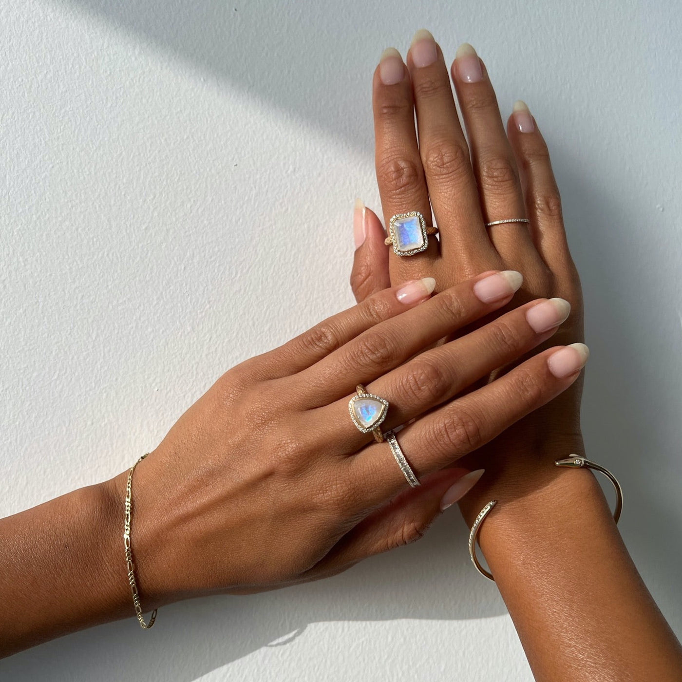 Hand model wearing two yellow gold rings with moonstone center stones.